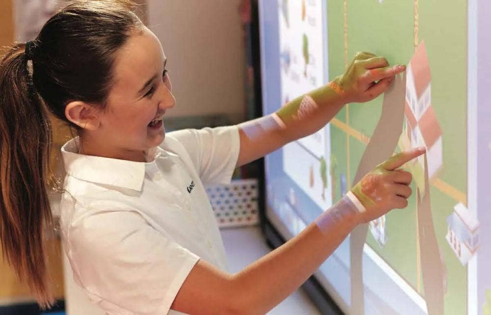 young female student moving objects on activboard interactive whiteboard
