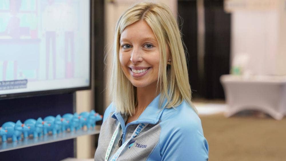 young woman standing next to a screen, smiling and looking at the camera