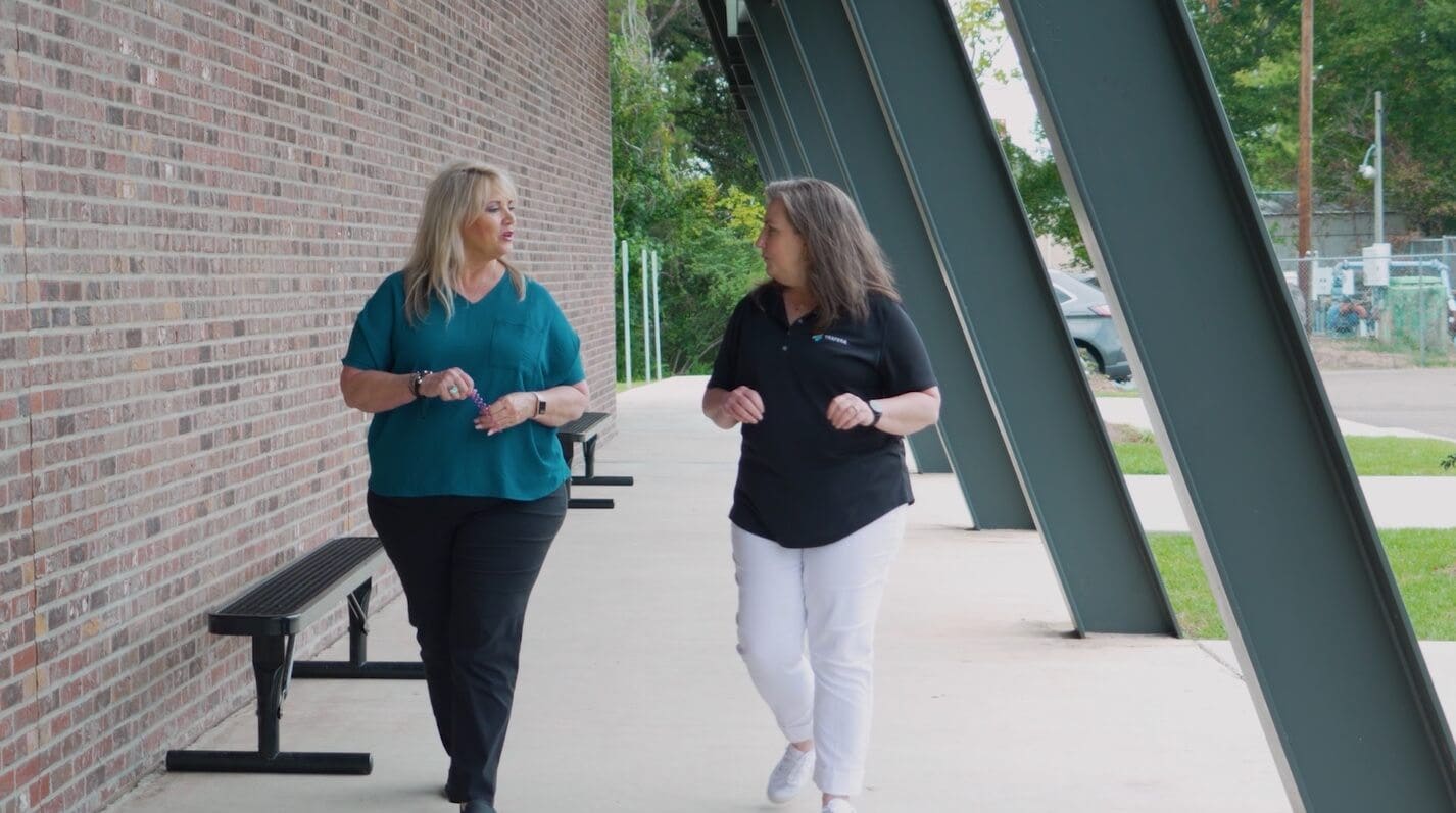 Two teachers talking to each other and walking outside the gym
